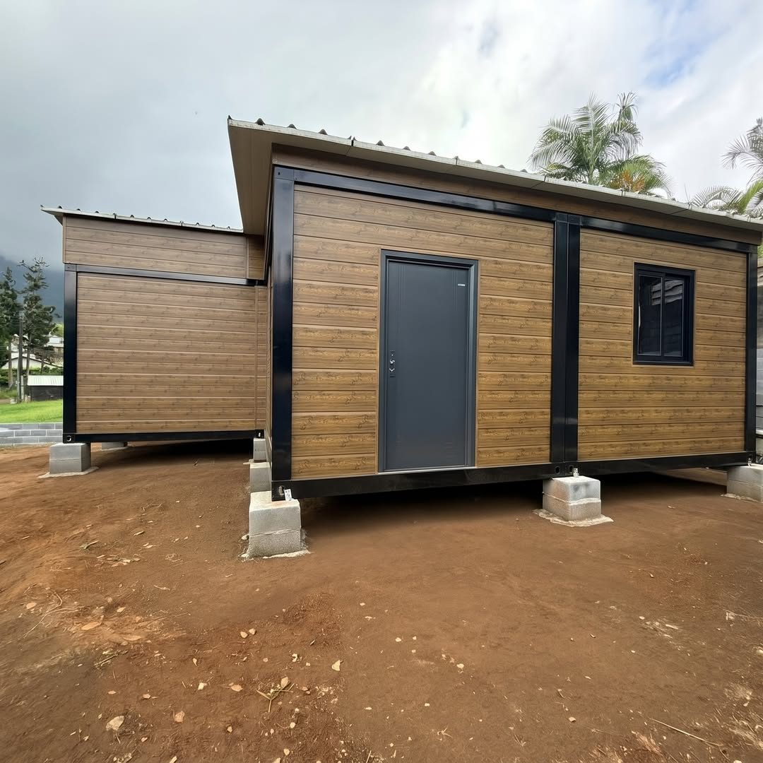 Module habitable à bardage effet bois avec porte grise et fenêtre, posé sur plots